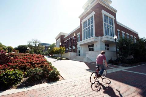 A student biking by the Colvard Student Union